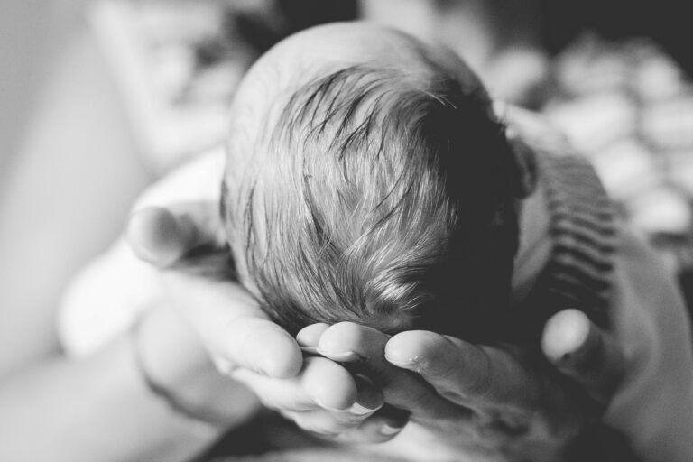 tête de bébé dans les mains de sa maman